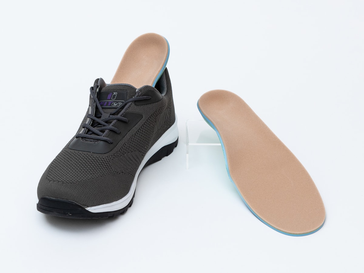 pair of custom orthotics inserted into a black athletic shoe