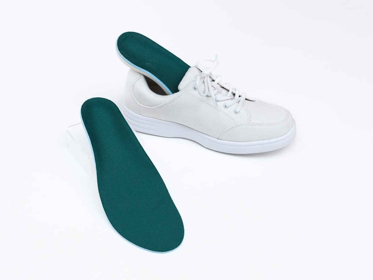 a green foot orthotic inside of a white shoe